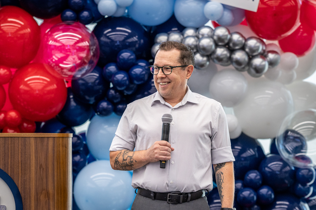 Dr. Layne Pethick smiling onstage with microphone