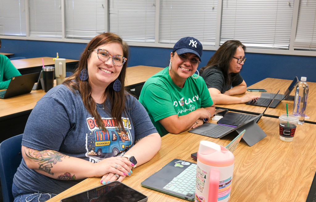 three teachers at table smiling at camera