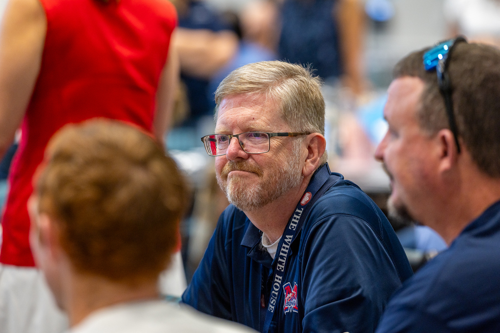 male teacher at table listening to colleague
