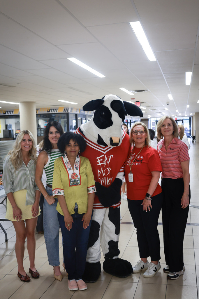 local. business partners stand with the chick-fil-a cow at the school supply drive