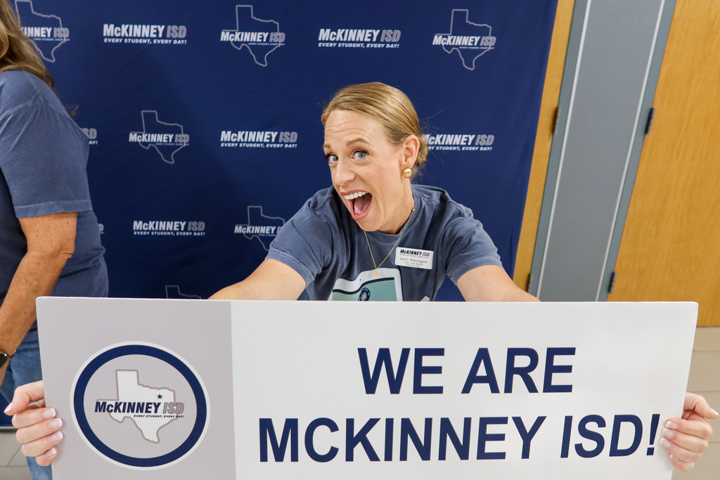 teacher smiling with sign that says we are mckinney isd