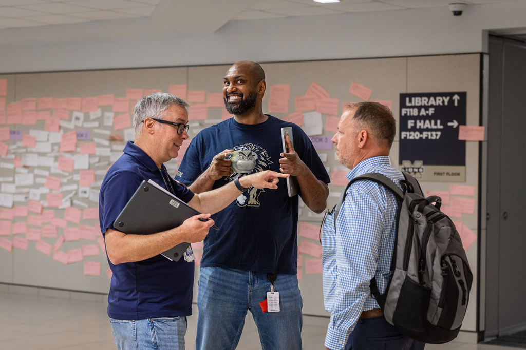 three admins talking while one smiles at camera