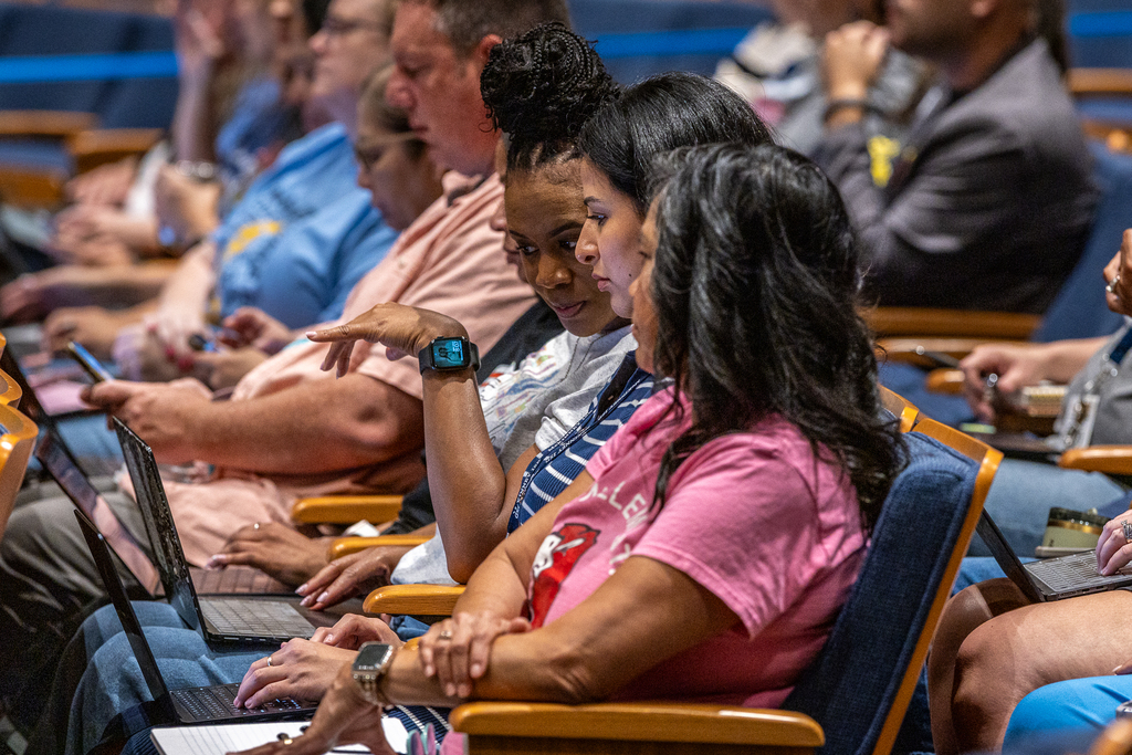 teachers in auditorium looking at computers