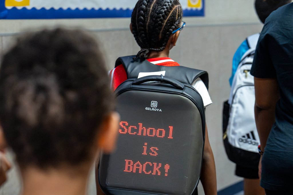 boy with backpack that reads School is Back in LED letters on it