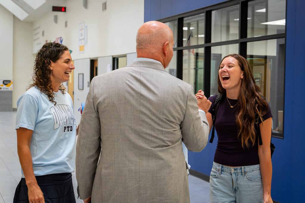 Shawn Pratt shaking hands with student who is laughing with him