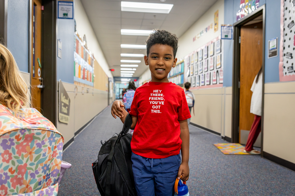 Boy standing in hall with shirt that reads Hey there, friend, you've got this