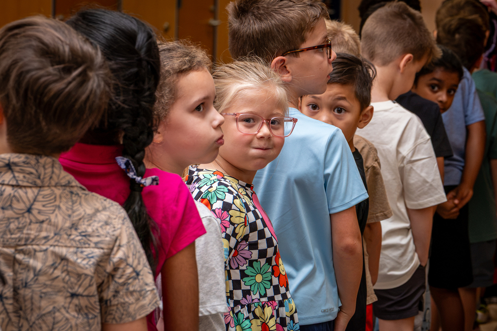 line of students with a girl and two boys looking back at camera