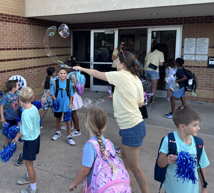 PTO rep blowing bubbles for students at front door