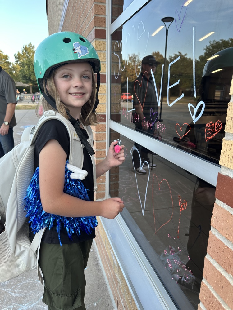 student writing positive message on window
