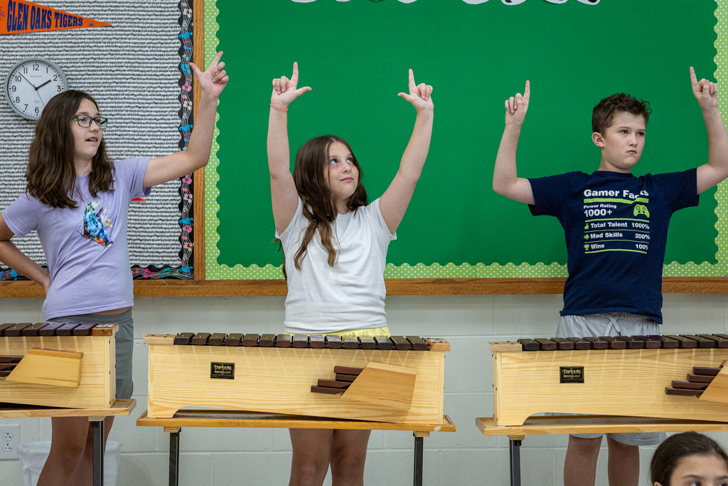 students holding up hands during xylophone lesson