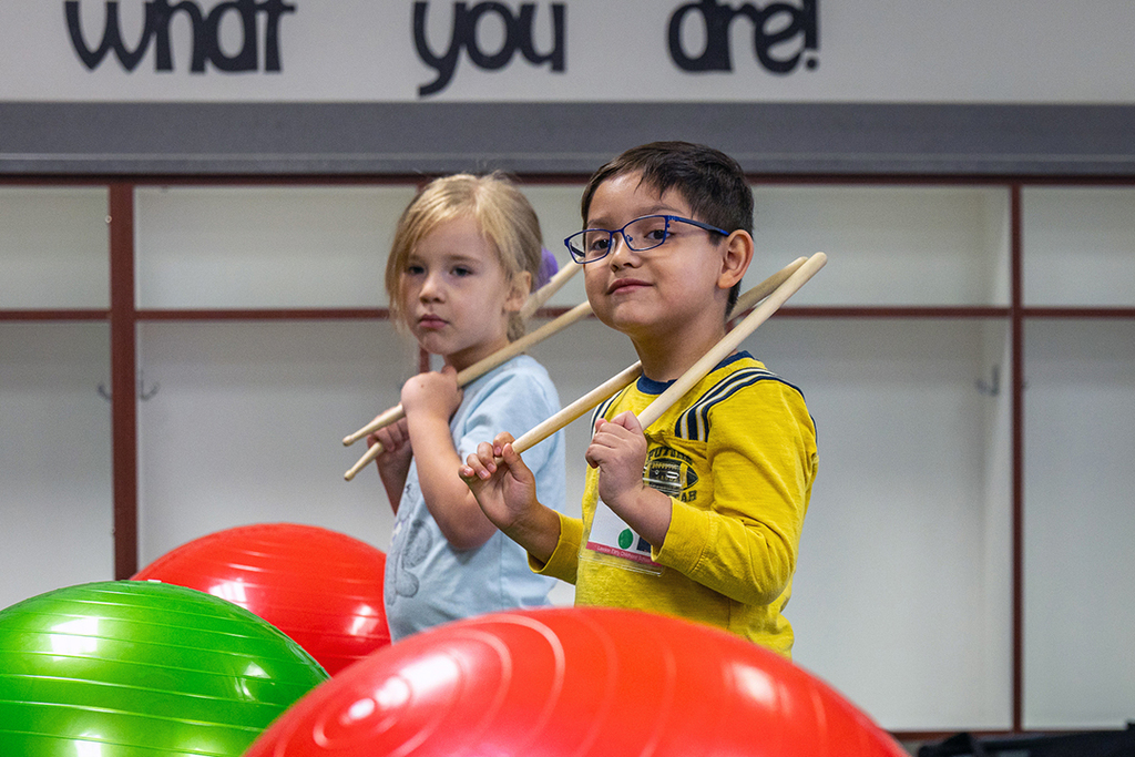 boy and girl holding drumsticks on their shoulders