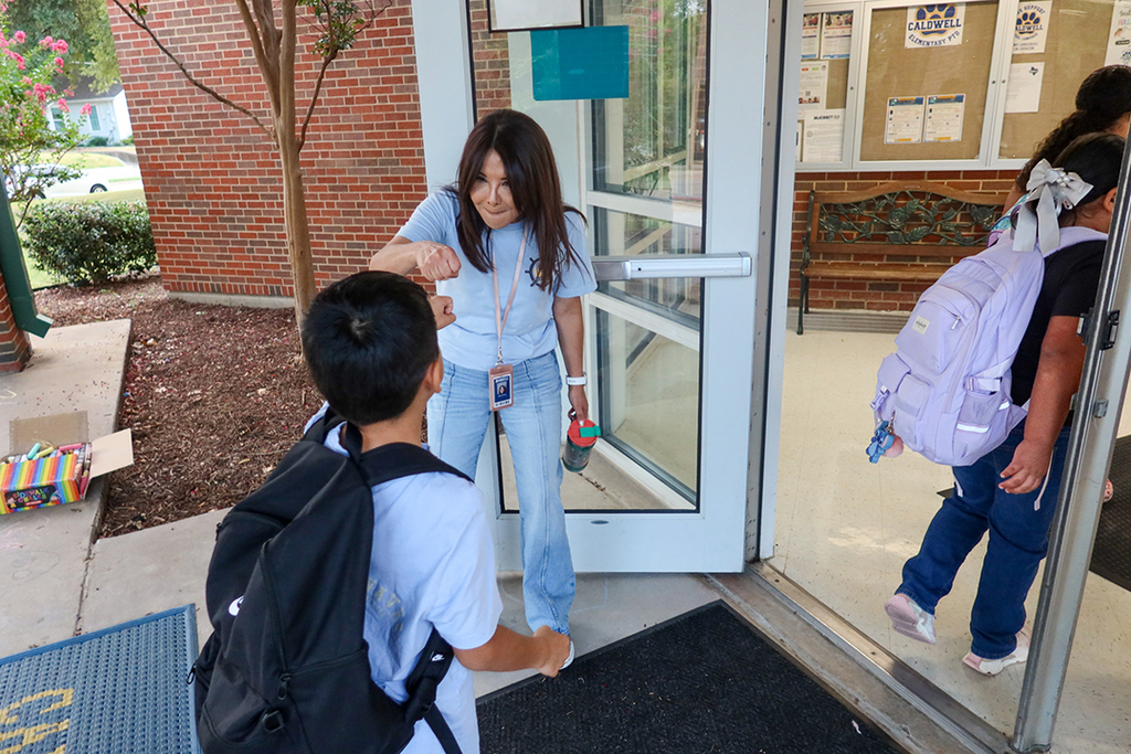 female teacher greeting students at door of Caldwell