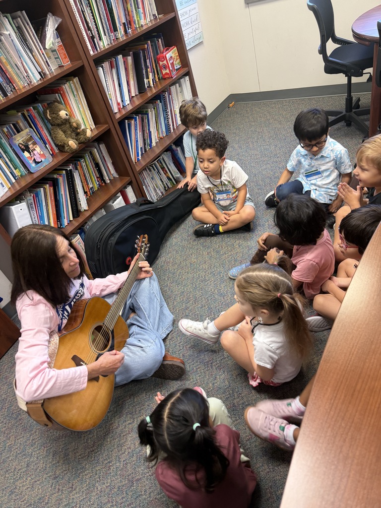 Mrs. Towber is playing guitar for a group of students