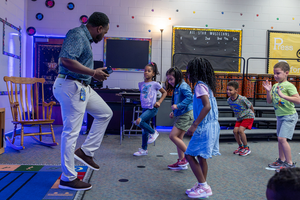 students dancing to song as teacher leads them