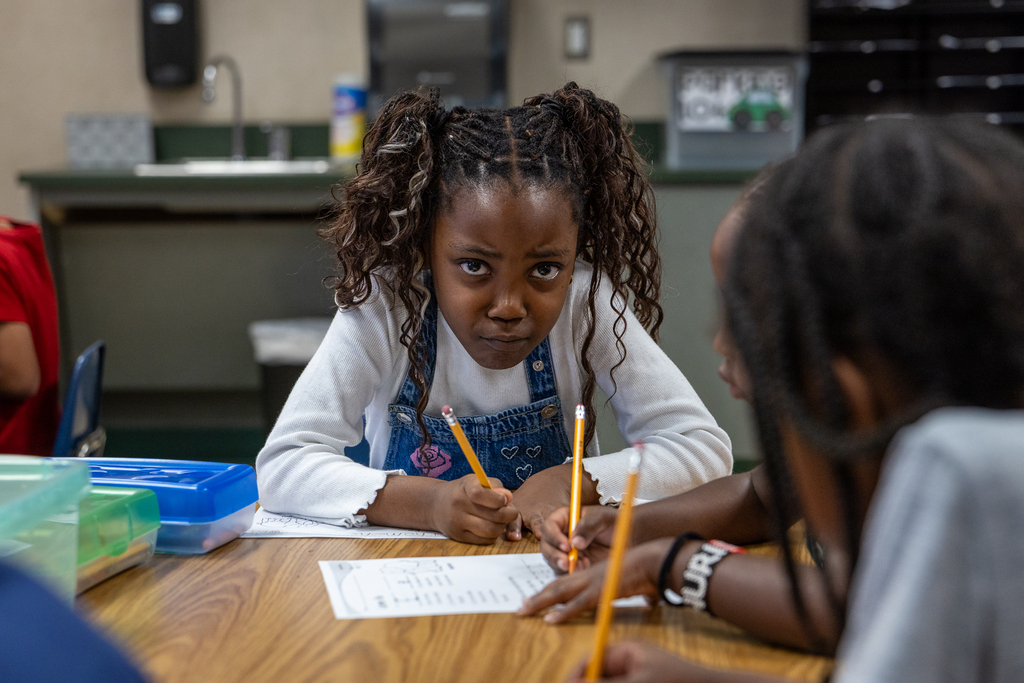 student looking at camera as she works at her desk