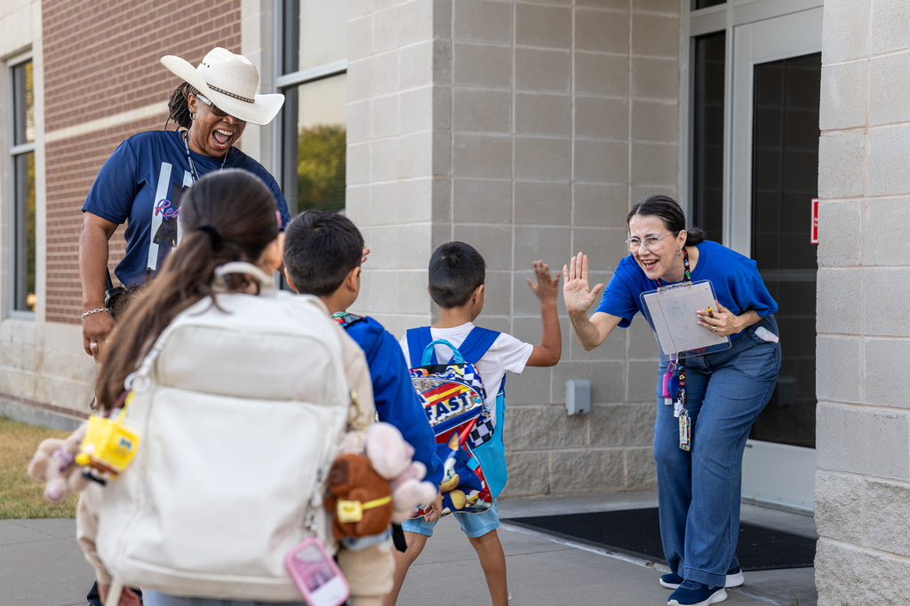 ASO and teacher greeting students as they enter the building