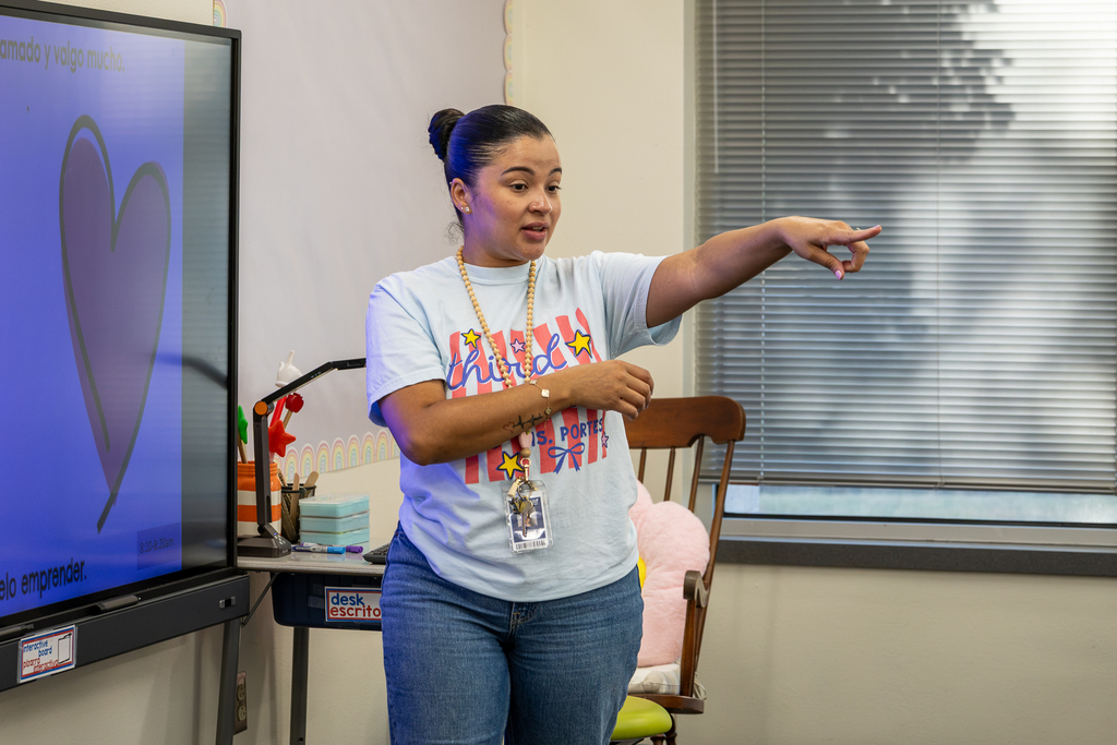 teacher in class gesturing as she leads a lesson