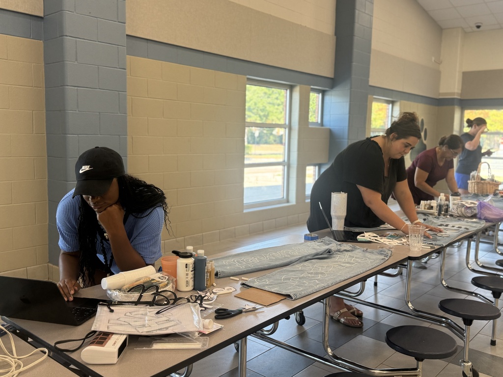 Teachers at a long table designing spirit jeans