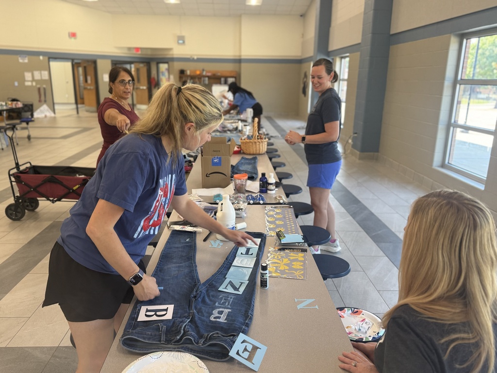 Additional image of teachers at long table adding letters to spirit wear