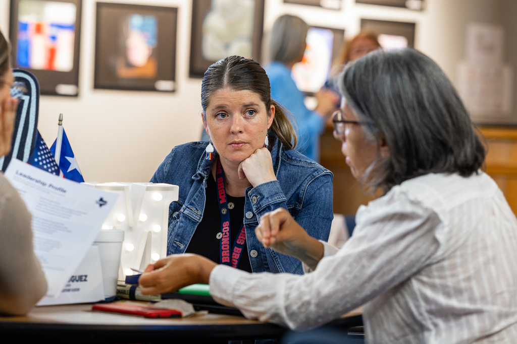 two women at table discussing topic