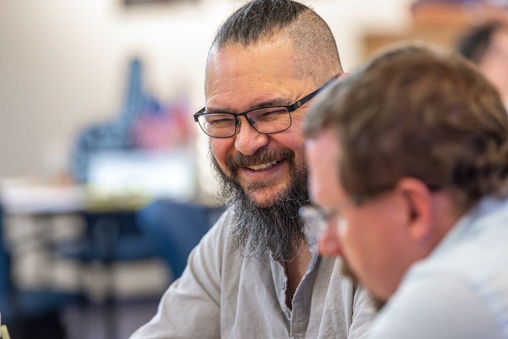 male participant at table laughing with colleagues