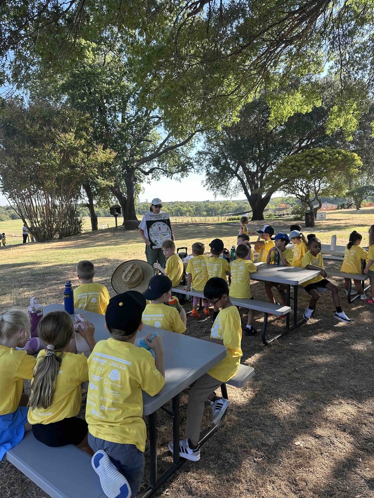 Three - four tables of students listening to instructor during field trip