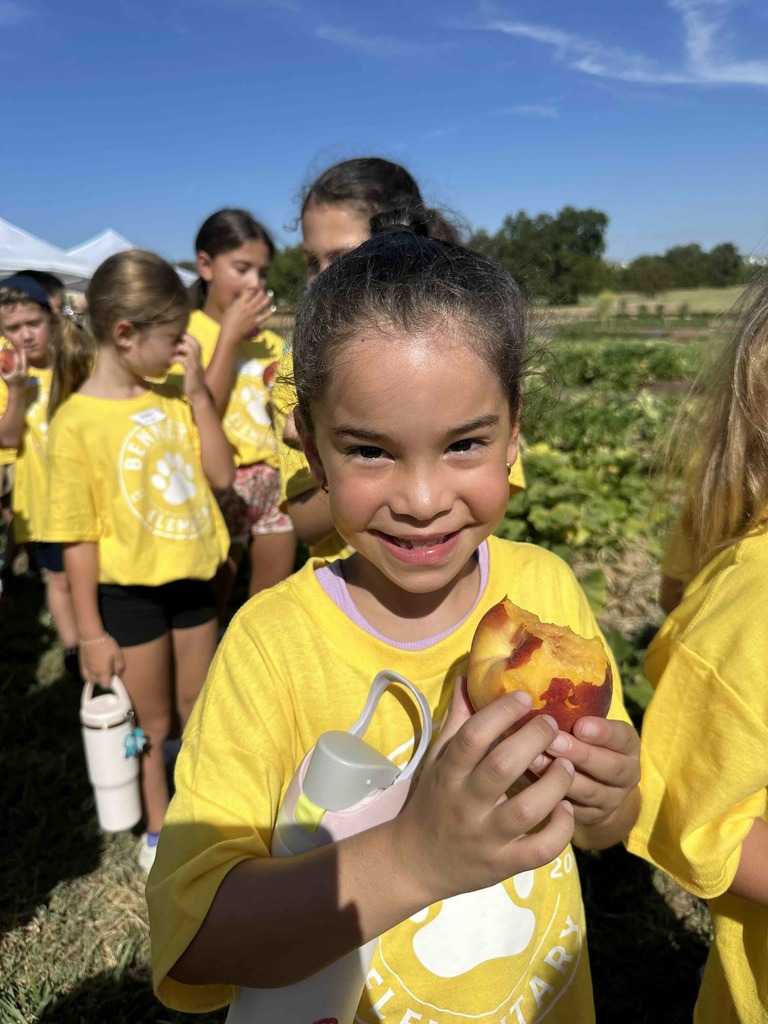 One student enjoying a fresh peach with other students in the background