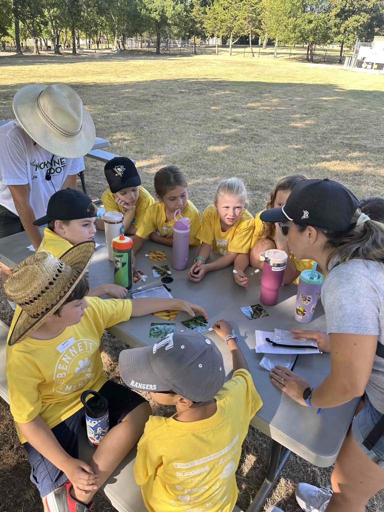 Group of students gathered around a table listening to directions from an instructor