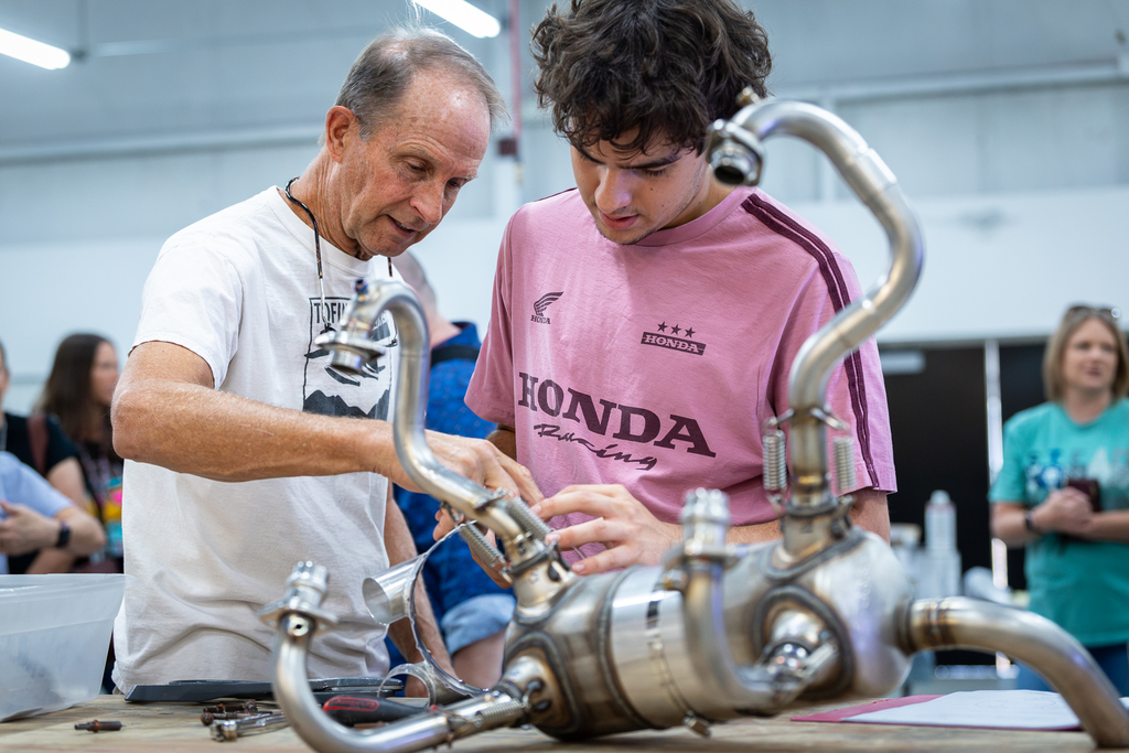 aviation mentor and student looking closely at a piece of engine machinery in the aviation facility
