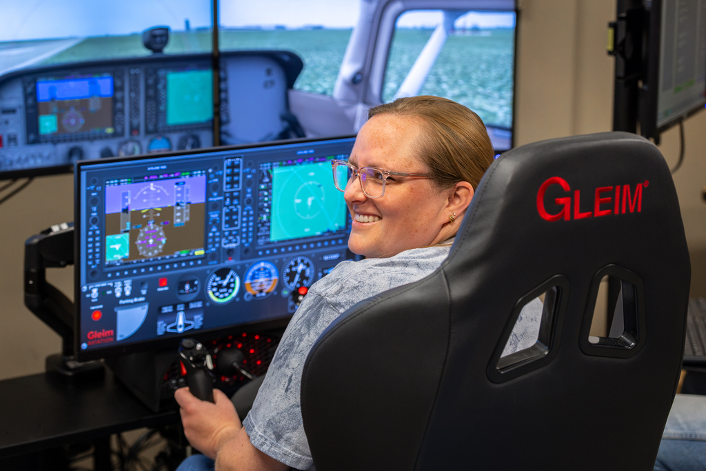 teacher in aviation simulator looking back over her shoulder and smilng