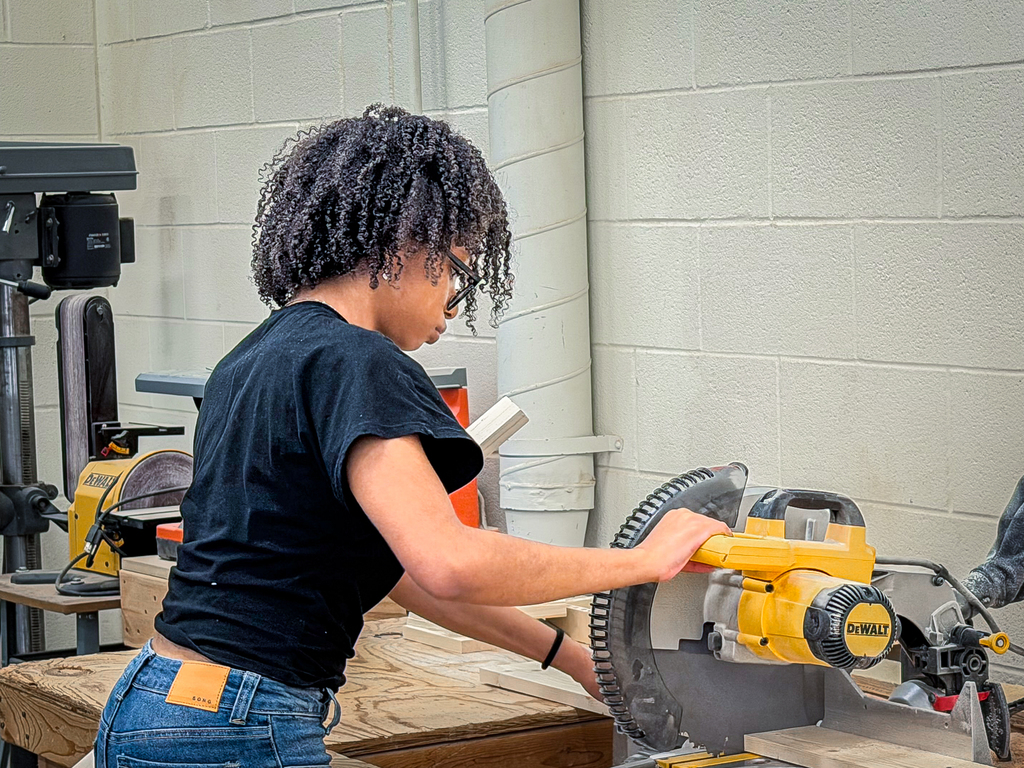female student operating a circular table saw