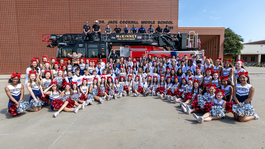 cheerleaders and PALS in front of fire truck with officers and firefighters on top of truck