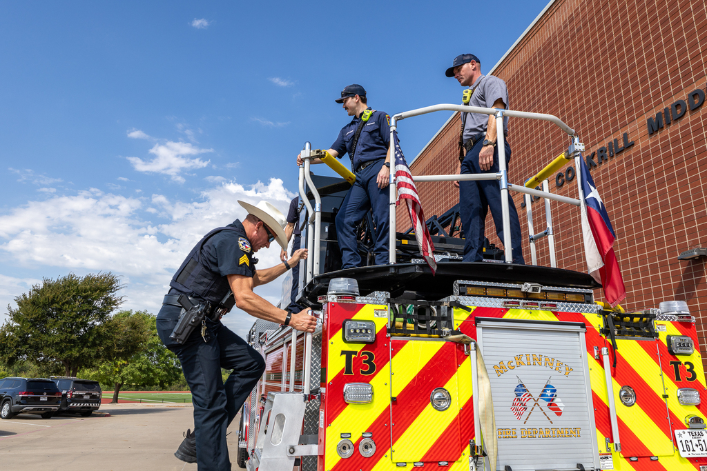 officer in cowboy hat climbing down from fire truck