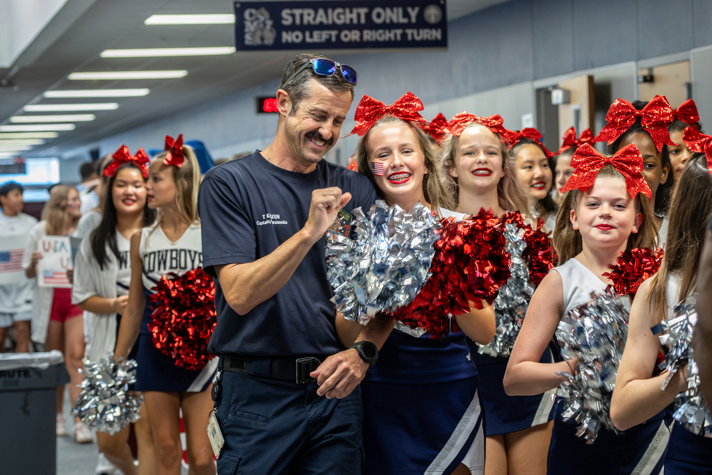 firefighter walking with his daughter who is a cheerleader and laughing with her