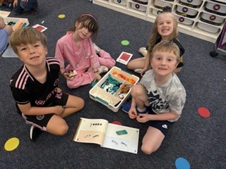 Group of 1st graders smiling for the camera with their lego kit