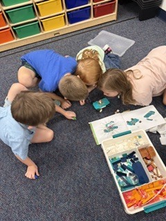 Group of 1st graders peering down at their lego build