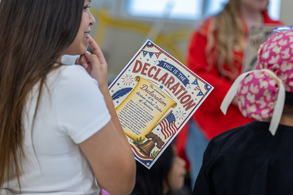 girl holding card that has the declaration of independence on it
