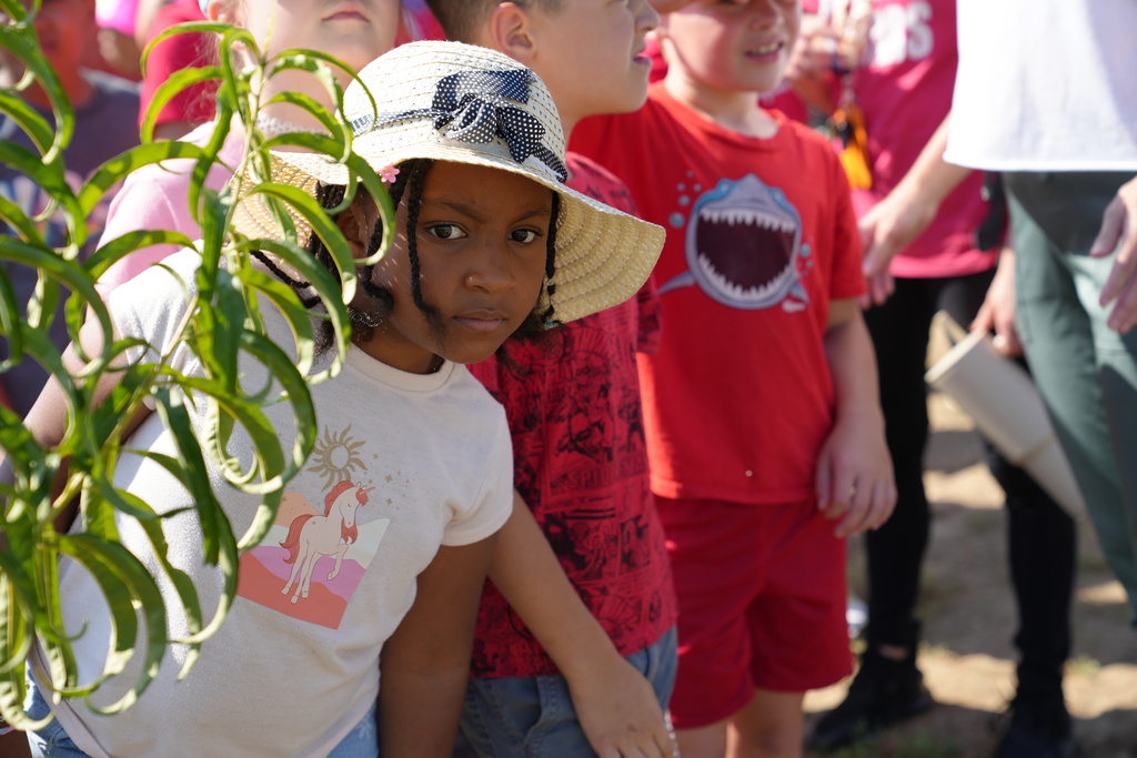 A student from Vega Elementary peeks around a tree branch at the McKinney Roots farm.