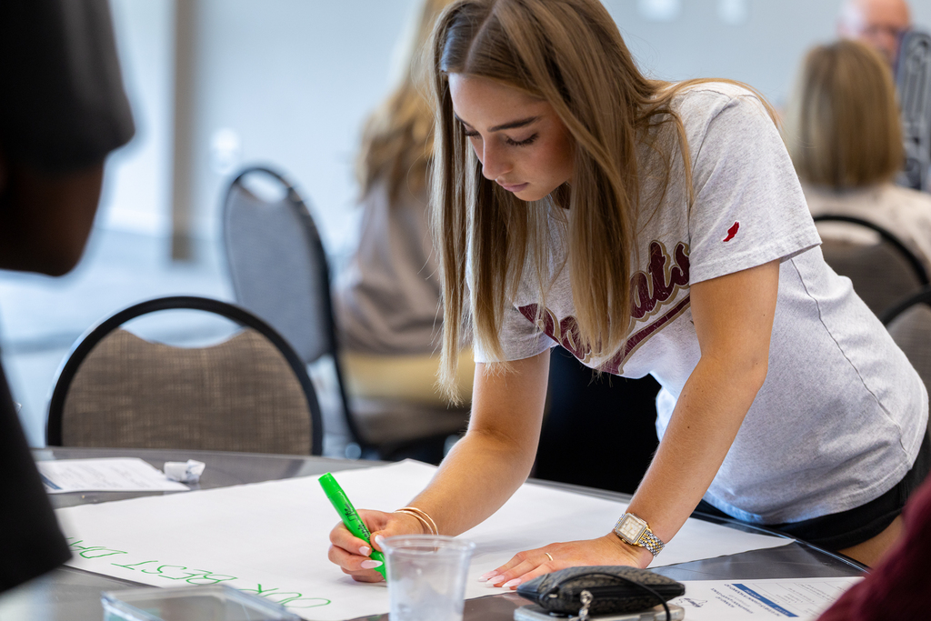 female student writing on butcher paper at table