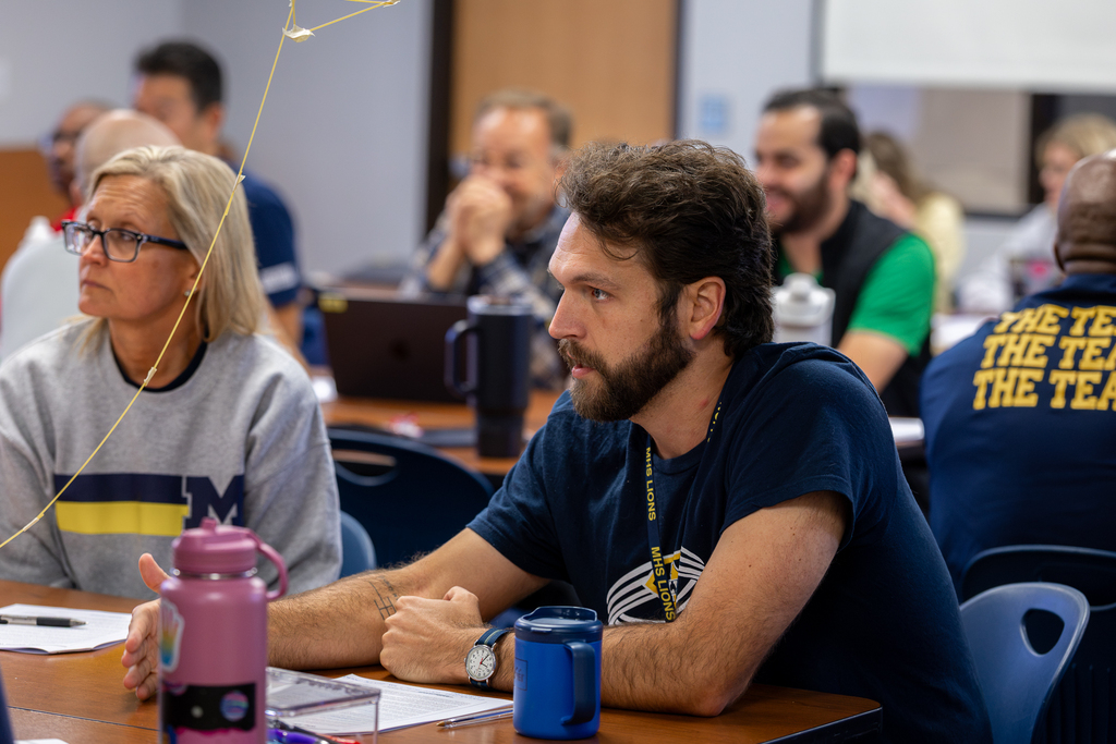 male teacher talking at table during session