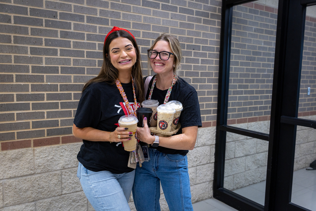two female teachers at North holding armful of coffees