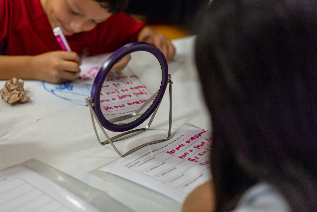 girl and boy trying to read and write while looking in a mirrore