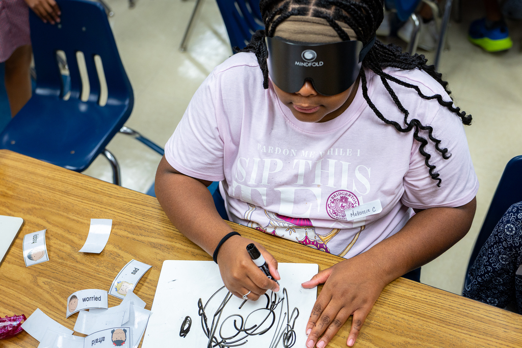 girl trying to draw while wearing a blindfold