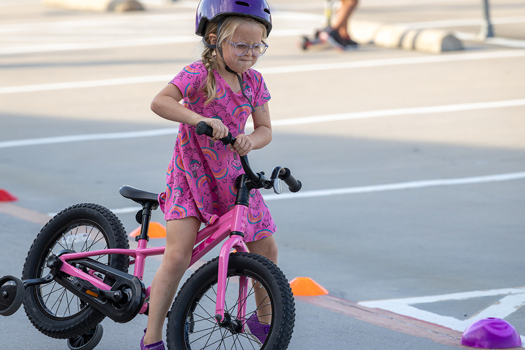 girl straining to lift her bike upright