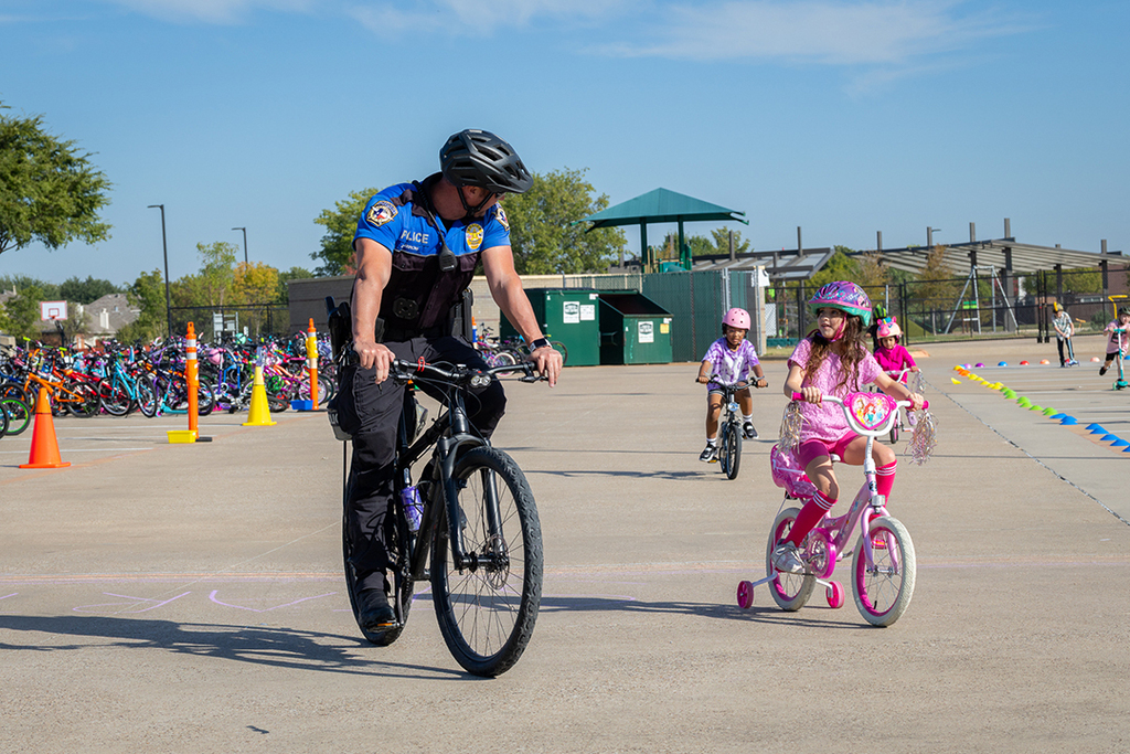 police officer riding bike next to girl riding her bike and talking to one another