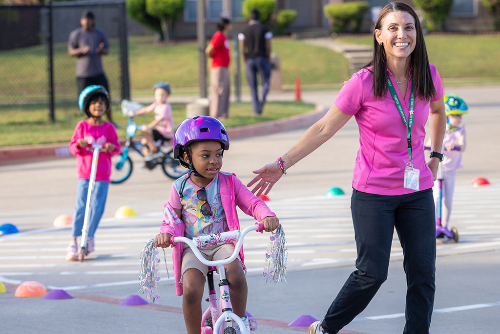 teacher smiling and helping student on her bike