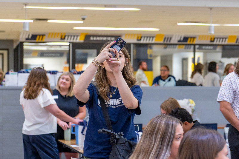 student with phone holding it up to take a video