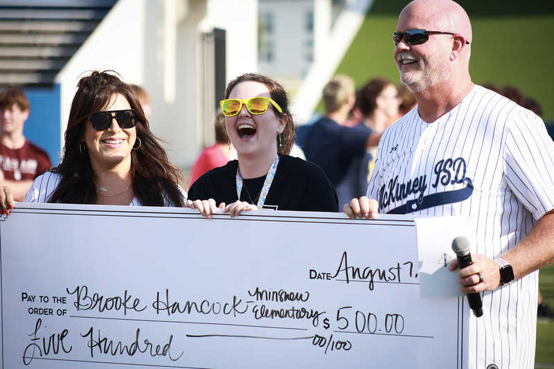 teacher with Pratt holding $500 check