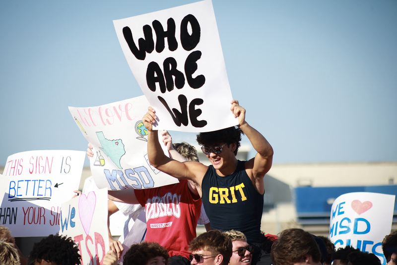 male student holding sign  and cheering