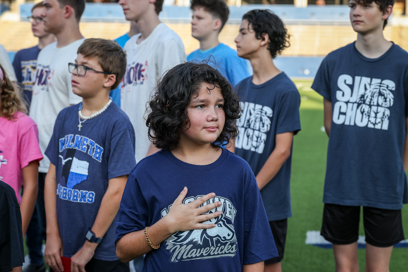 elementary choir student with hand on hear during anthem